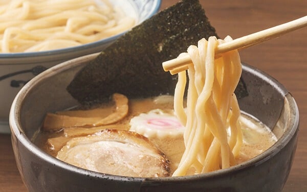 Tsukemen com massa grossa sendo mergulhada em caldo concentrado, servido separado para preservar a textura.