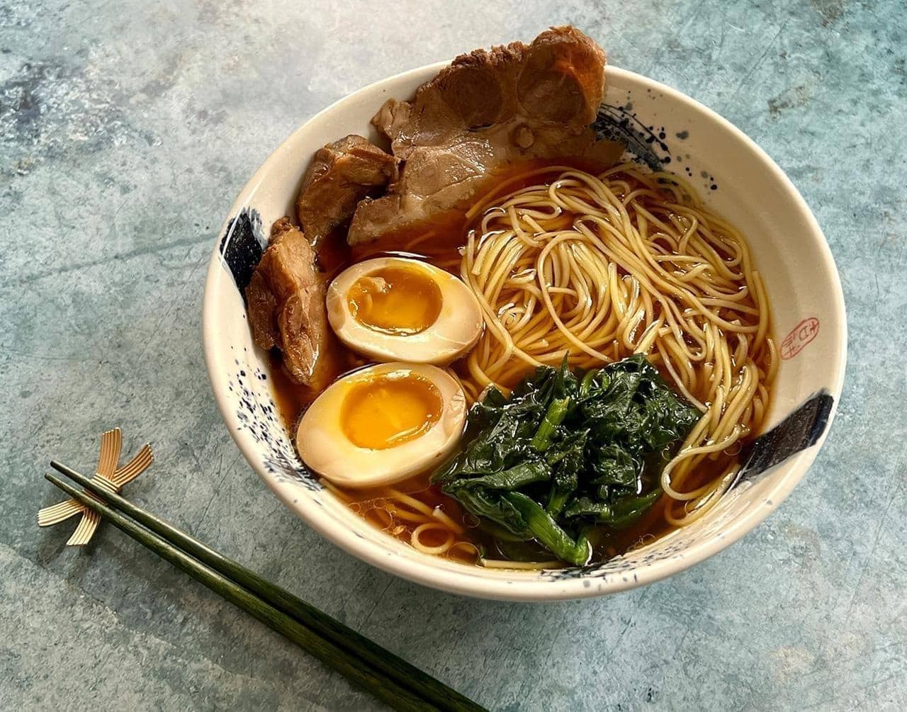 Tigela de ramen com caldo dourado, macarrão Keishi, carne suculenta, ovo e vegetais coloridos, destacando brilho, textura e apresentação típica da marca
