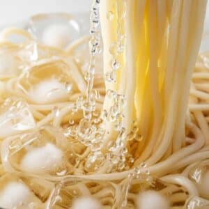 Tigela de macarrão udon com fios grossos em caldo quente, acompanhamentos japoneses e apresentação artesanal, destacando a qualidade e autenticidade das massas Keishi.