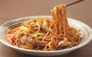 Macarrão de yakissoba salteado com legumes coloridos e proteínas, envolto em molho brilhante, destacando textura e qualidade da linha profissional de yakissoba da Keishi.